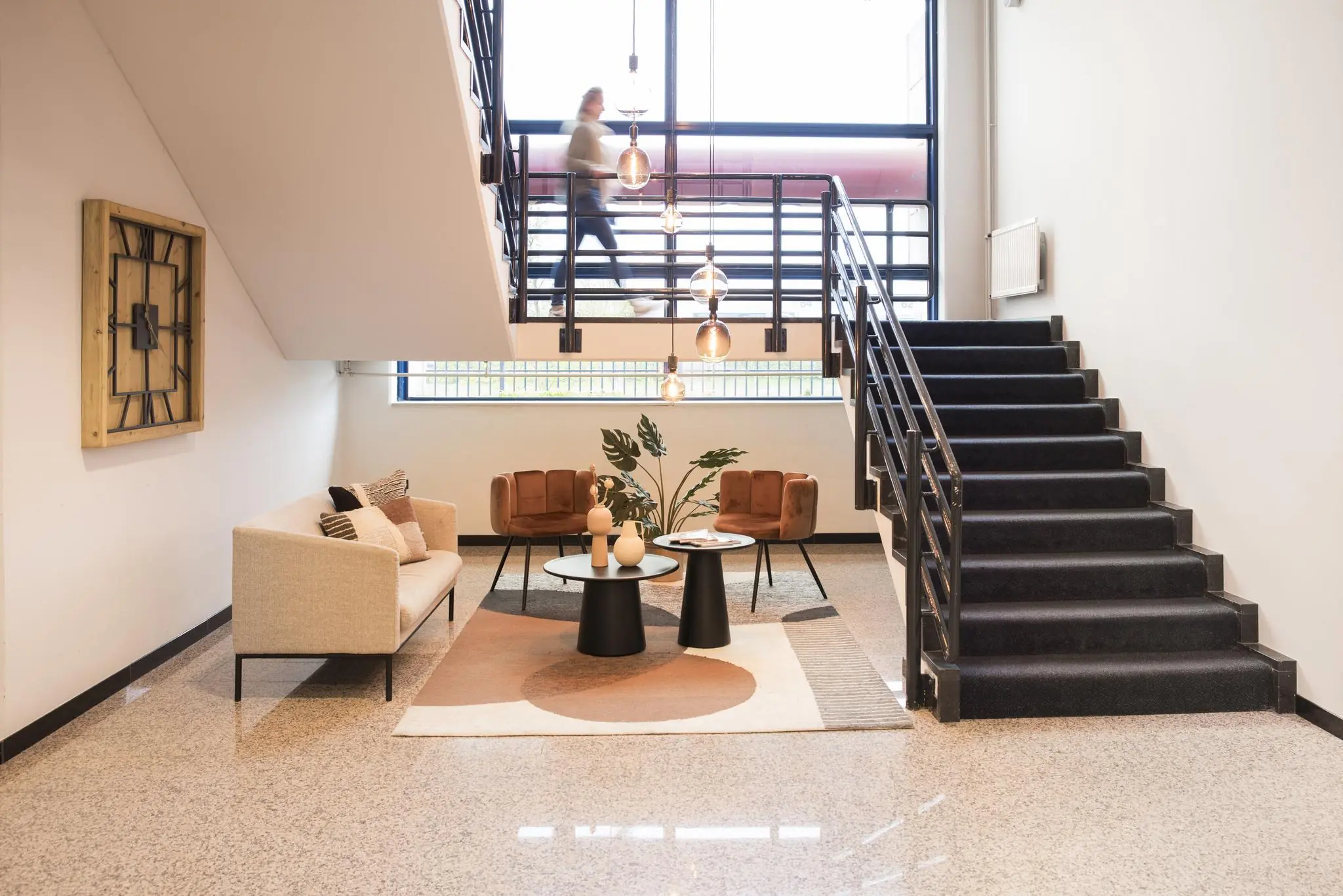 Moderne wachtruimte onder een trap in het kantoorgebouw aan Markerkant 13, met sfeervolle meubels en hanglampen.